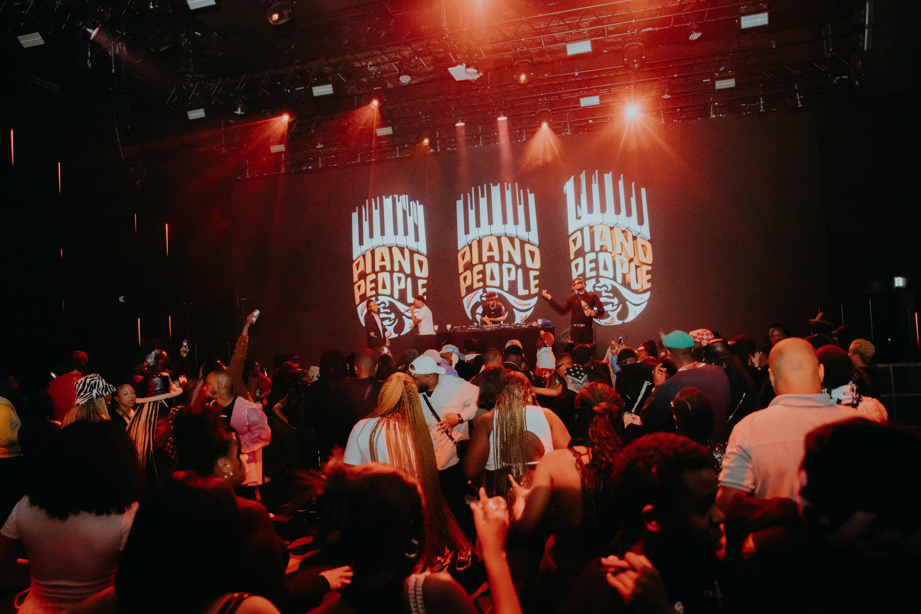 Archive performance photograph from a real Piano People amapiano event showing DJs and a dancing audience, not the upcoming Johannesburg show